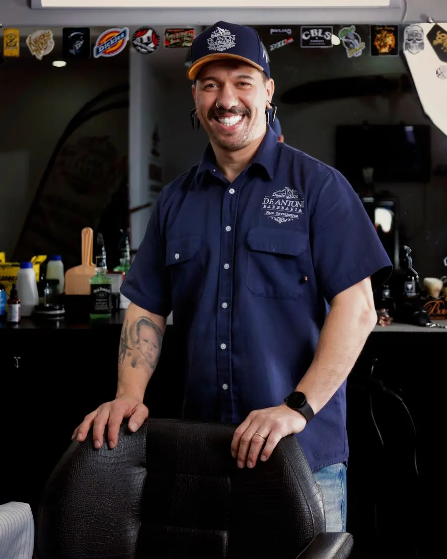 A smiling barber standing beside his chair