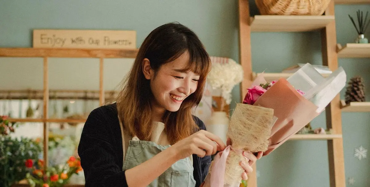 A florist wrapping a bouquet in her shop