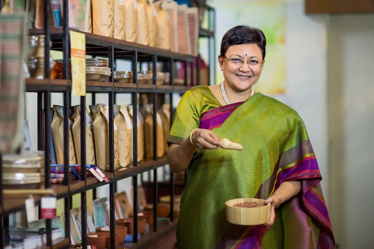 A grocer smiling among the shelves of her store